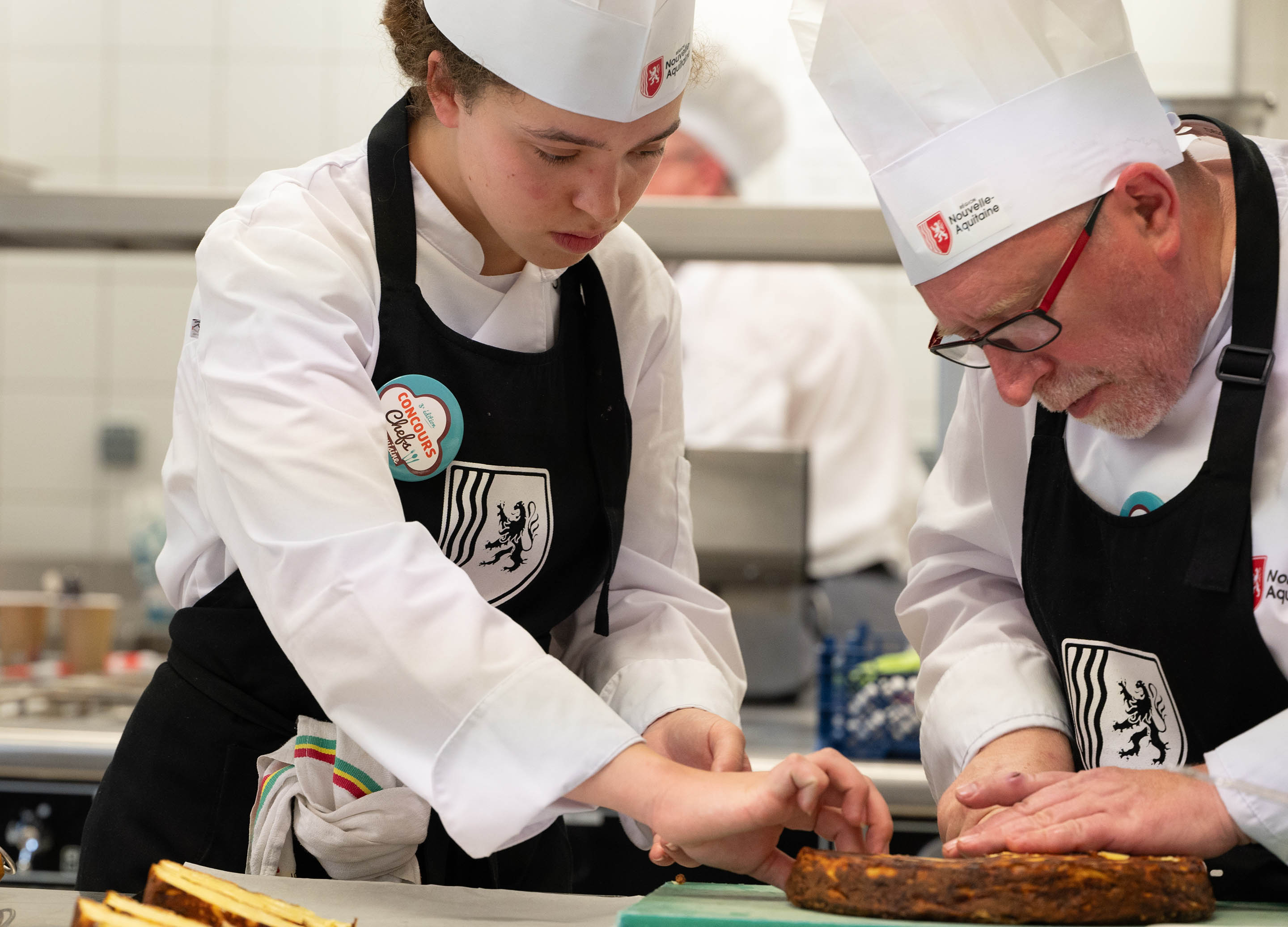 Concours des chefs 2023 - photo : un chef et une jeune apprentie en cuisine