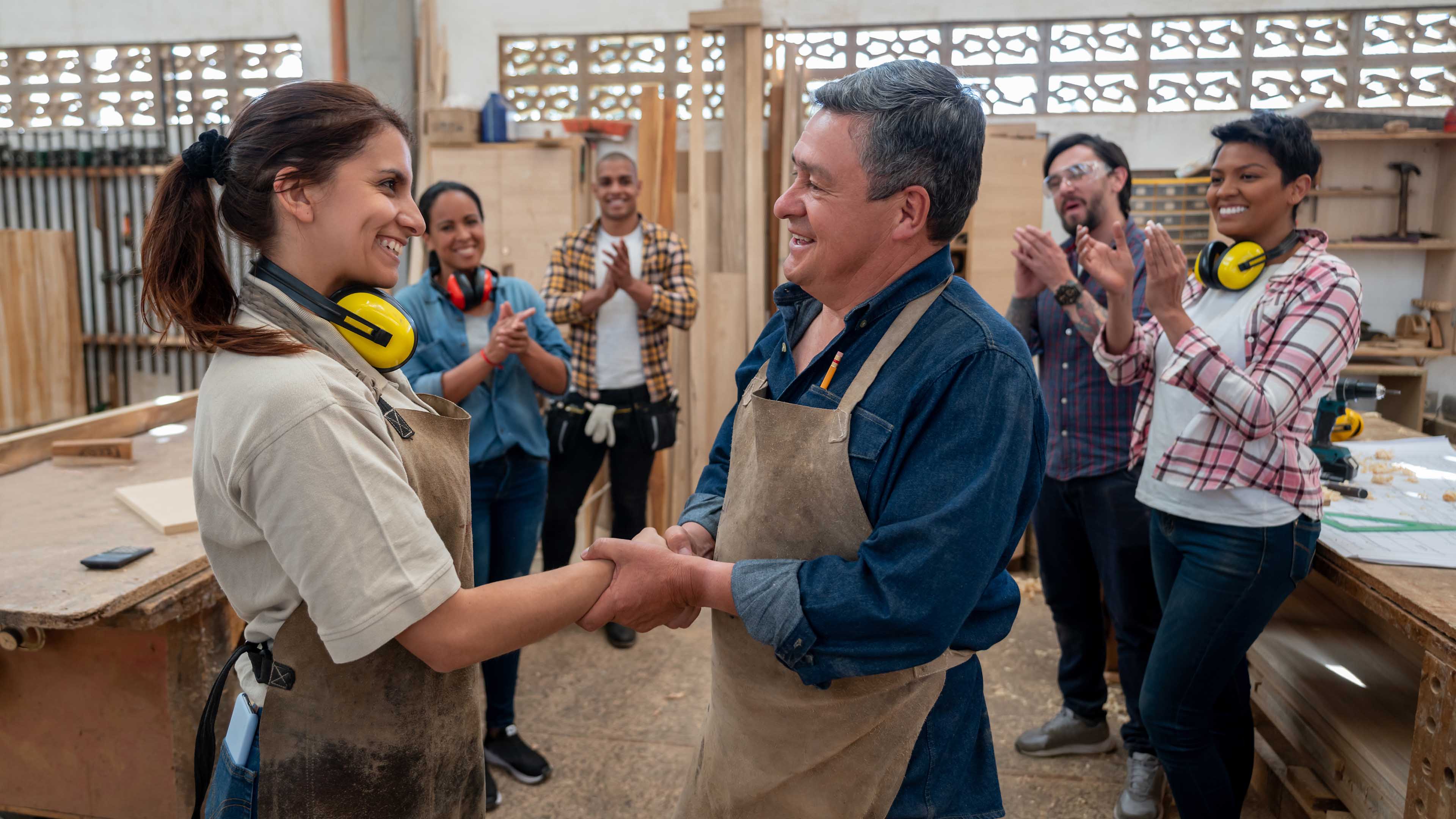 Homme et femme qui se serrent la main dans un atelier 