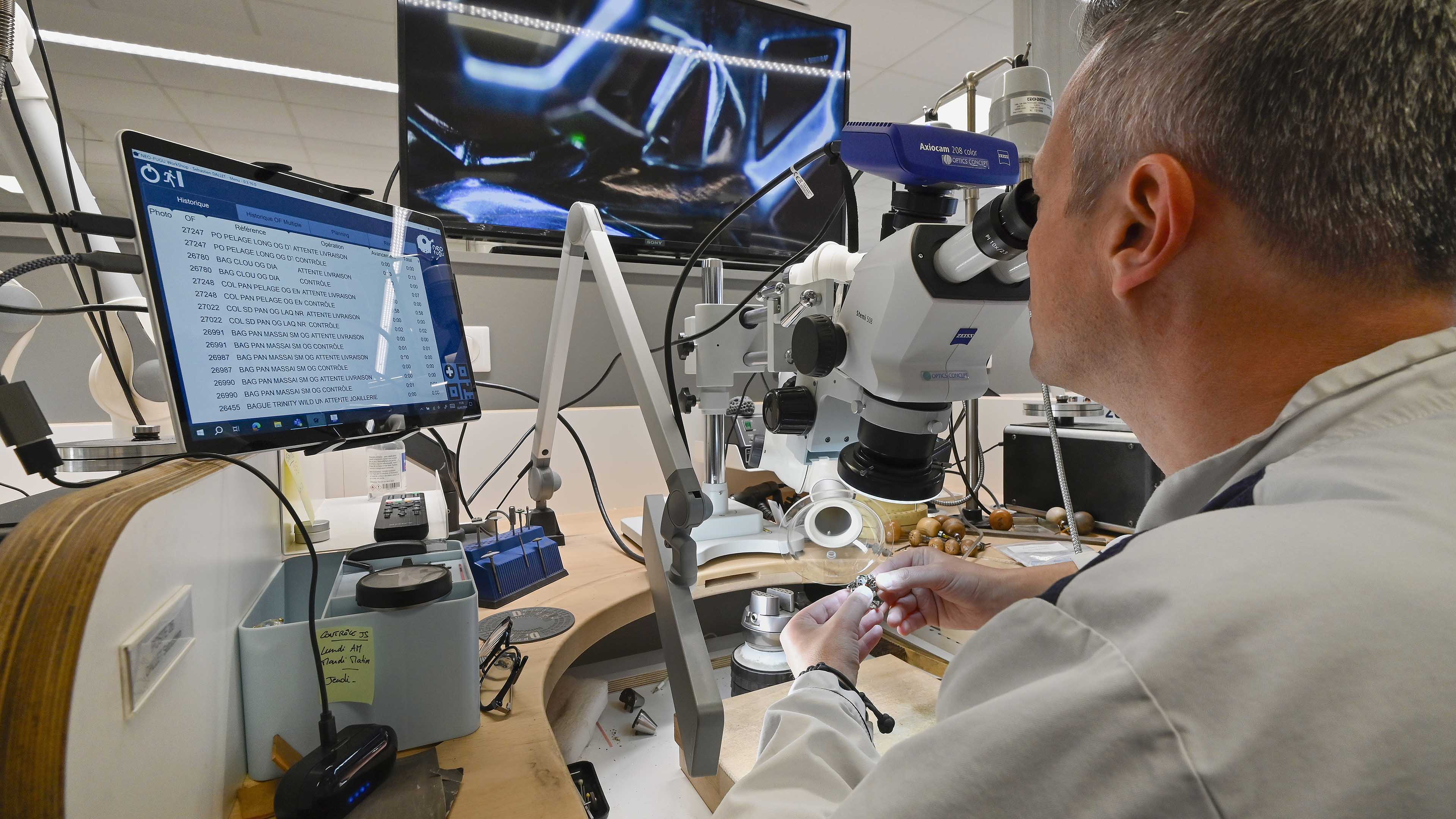 un homme examine un bijou au microscope