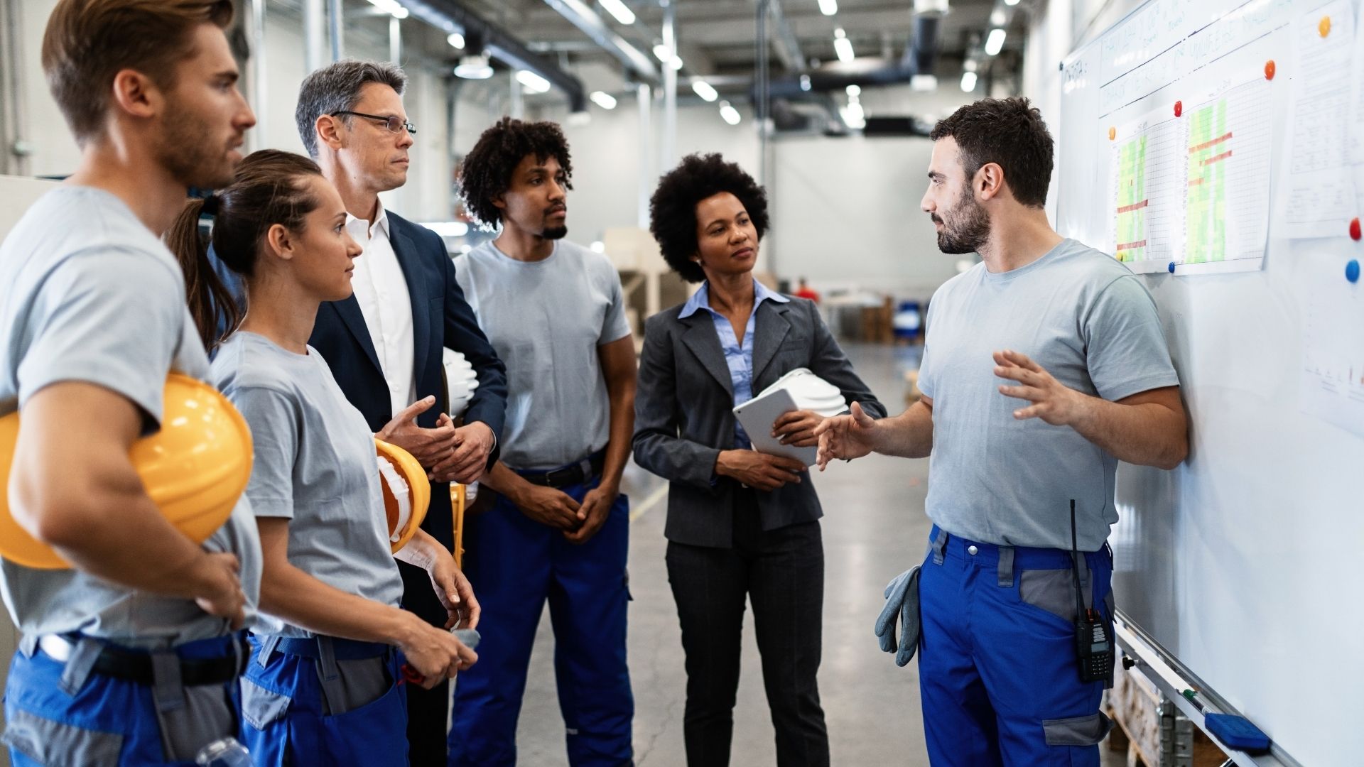 Personnes dans une usine devant tableau
